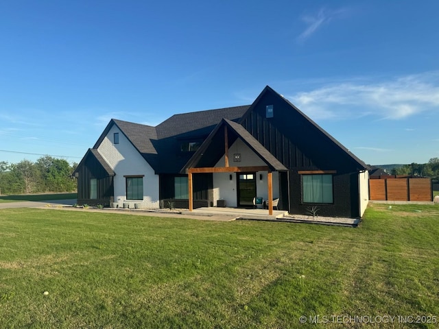 1583 E Clara Ct, Fort Gibson, OK 74434 - rear view of property with board and batten siding, fence, and a yard