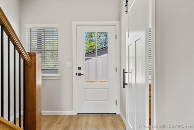entryway featuring baseboards, light wood-style flooring, and stairway