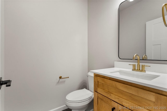 half bath featuring toilet, baseboards, and vanity