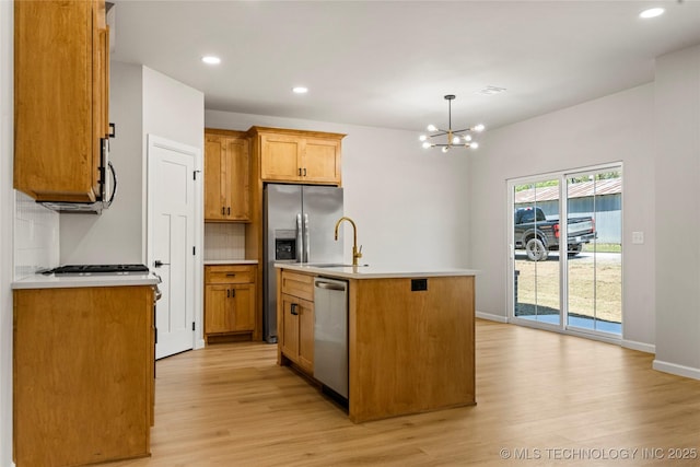 kitchen with decorative backsplash, light countertops, light wood finished floors, a chandelier, and stainless steel appliances