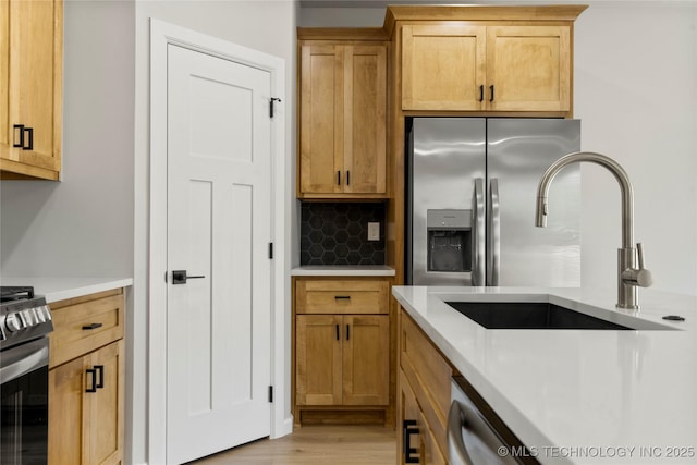 kitchen with decorative backsplash, appliances with stainless steel finishes, light wood-type flooring, a sink, and light countertops