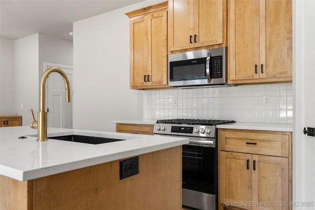 kitchen with appliances with stainless steel finishes, a sink, light countertops, an island with sink, and decorative backsplash