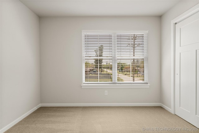 empty room with baseboards, plenty of natural light, and light colored carpet