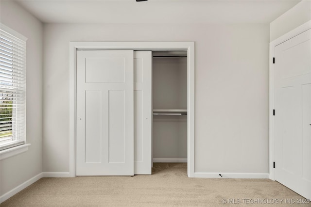 unfurnished bedroom with baseboards, light carpet, and a closet