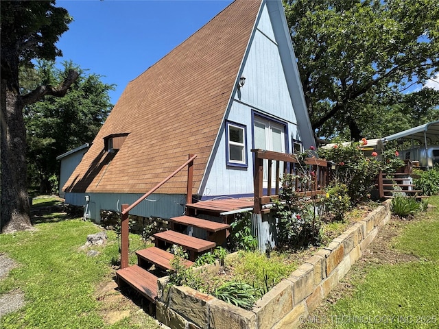 exterior space with roof with shingles, a wooden deck, and a yard