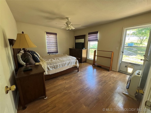bedroom with baseboards, ceiling fan, multiple windows, and wood finished floors