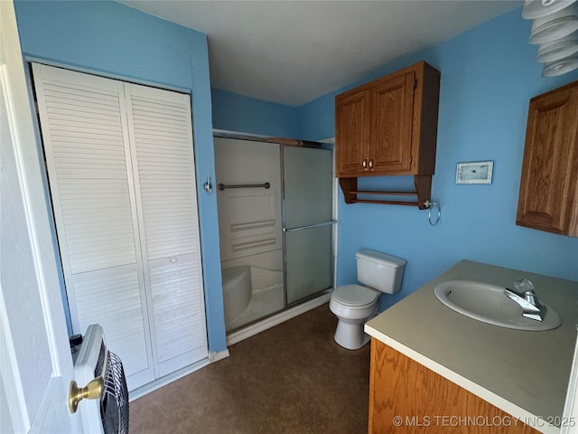 bathroom featuring a closet, vanity, a shower stall, and toilet