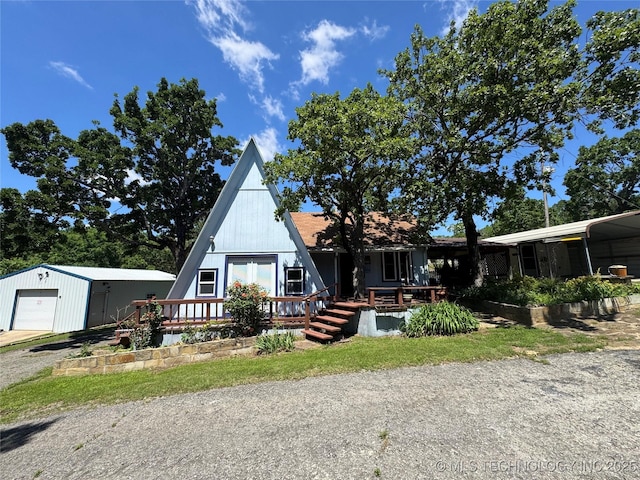 a-frame style home with a wooden deck, an outbuilding, driveway, and a detached garage