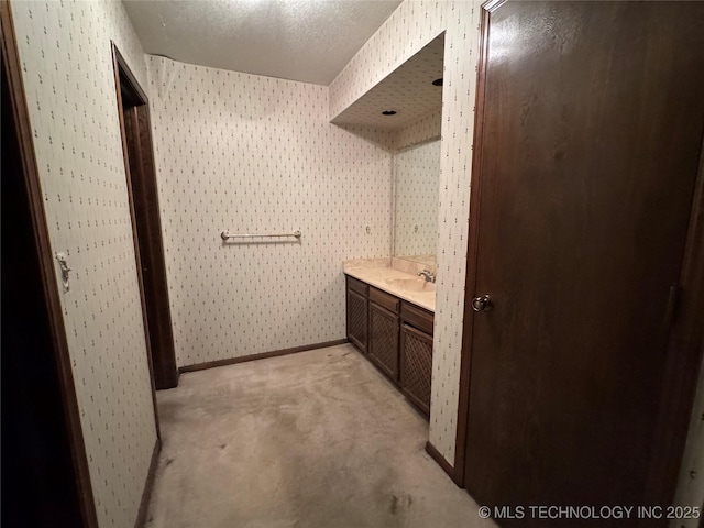 bathroom with vanity, baseboards, wallpapered walls, and a textured ceiling