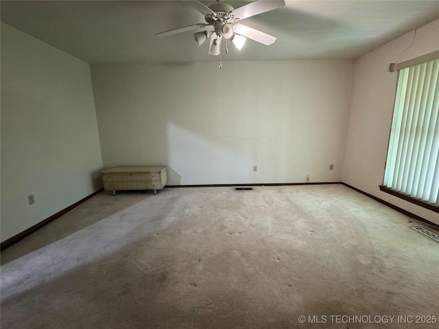 carpeted empty room with baseboards, a ceiling fan, and visible vents