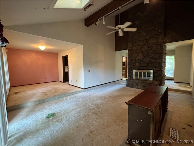 unfurnished living room featuring ceiling fan, high vaulted ceiling, a stone fireplace, carpet, and baseboards