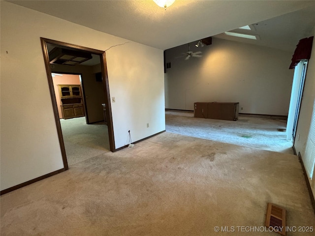 carpeted spare room with baseboards, ceiling fan, and visible vents