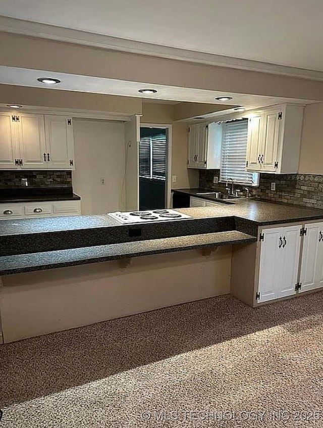 kitchen featuring a sink, backsplash, white cabinets, and dark countertops