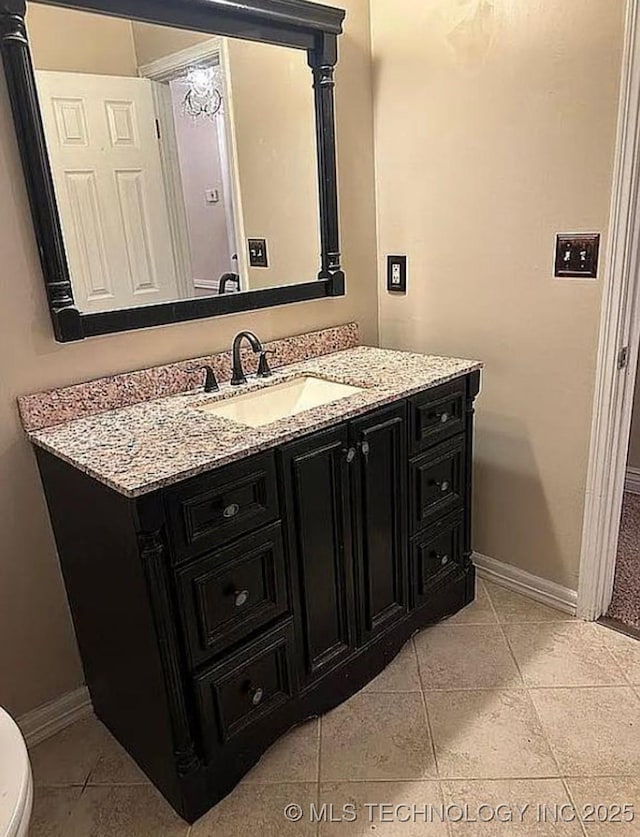 half bathroom with baseboards, vanity, tile patterned floors, and toilet