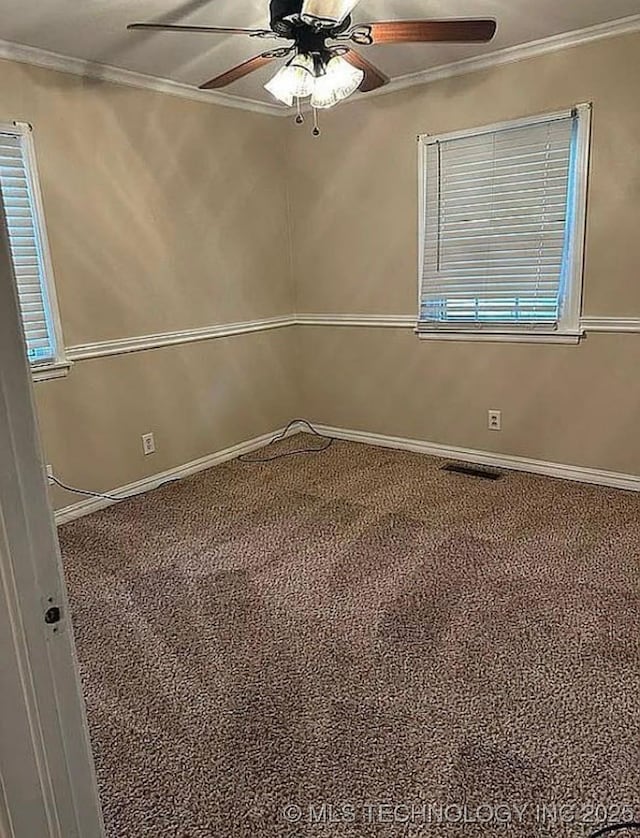 carpeted empty room with crown molding, baseboards, and ceiling fan