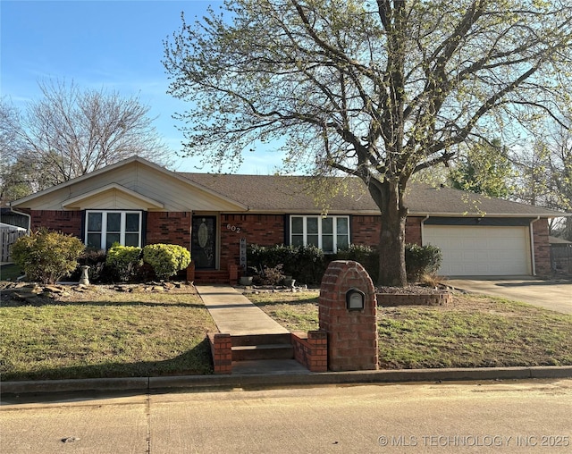 single story home featuring an attached garage, concrete driveway, a front lawn, and brick siding