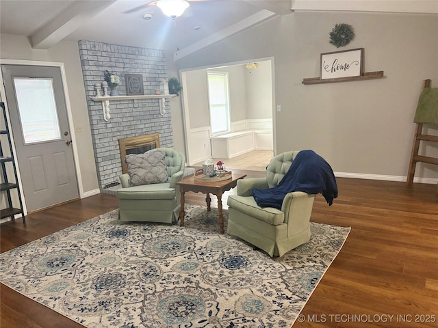 living room with wainscoting, wood finished floors, a fireplace, baseboards, and lofted ceiling with beams