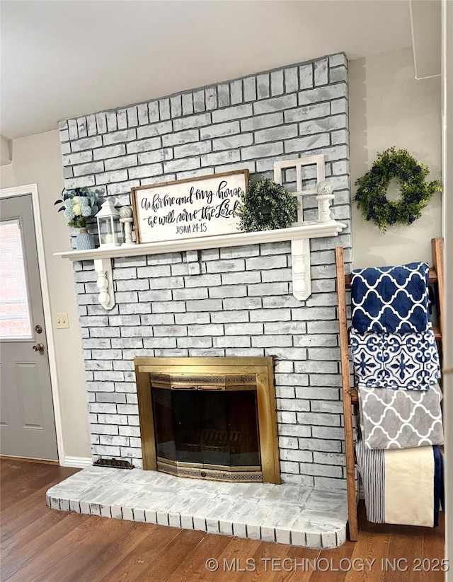 room details with a brick fireplace, baseboards, and wood finished floors