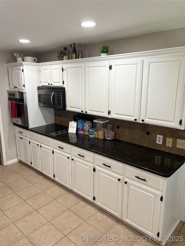 kitchen featuring white cabinets, oven, light tile patterned floors, and tasteful backsplash