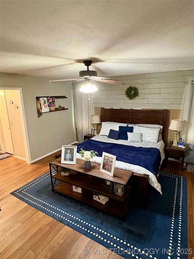 bedroom with baseboards, a ceiling fan, a textured ceiling, and wood finished floors