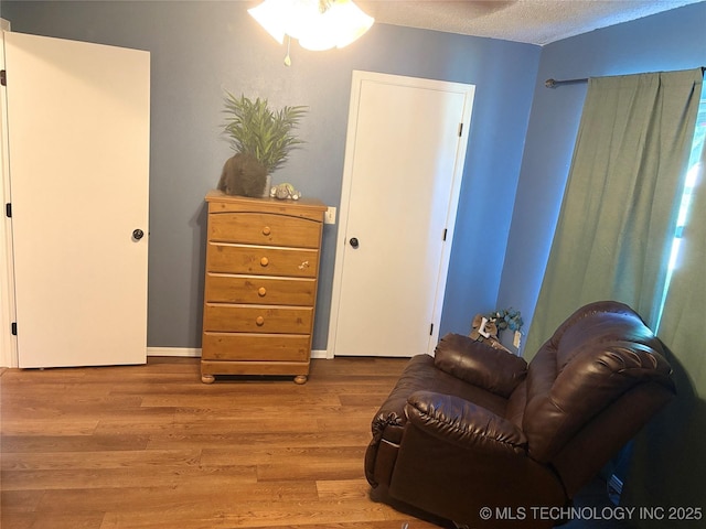 sitting room with a ceiling fan, a textured ceiling, and wood finished floors