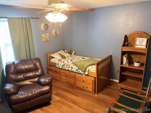 bedroom featuring a ceiling fan, a textured ceiling, and wood finished floors