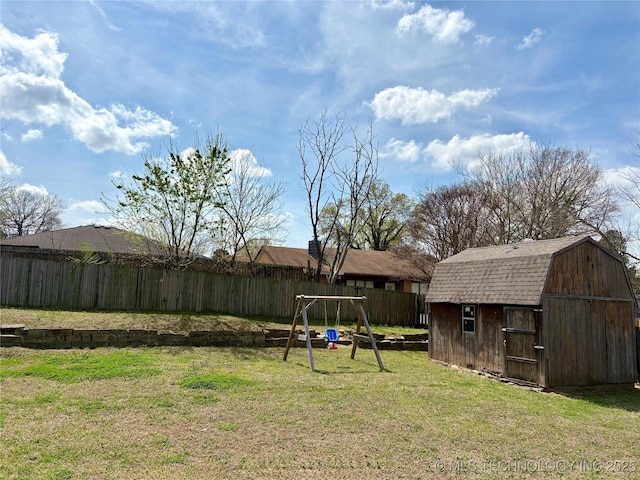 view of yard featuring a playground, a storage unit, an outdoor structure, and a fenced backyard