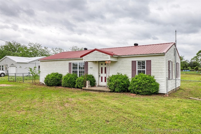 view of front of home with fence, metal roof, and a front lawn