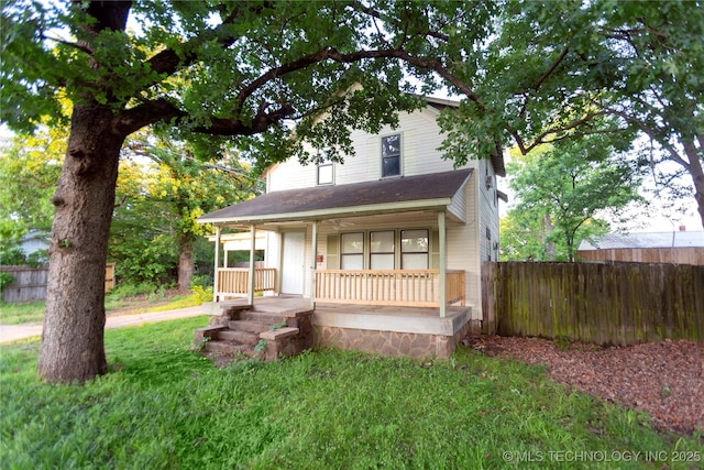 bungalow-style home featuring covered porch, fence, and a front lawn