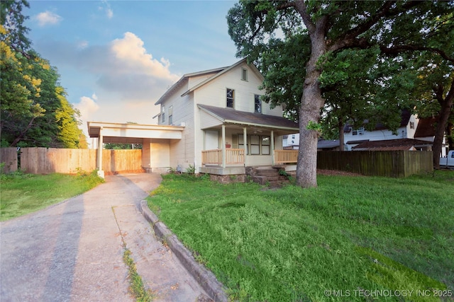 view of front of house with aphalt driveway, fence, a front yard, a porch, and a carport