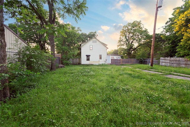 yard at dusk featuring a fenced backyard