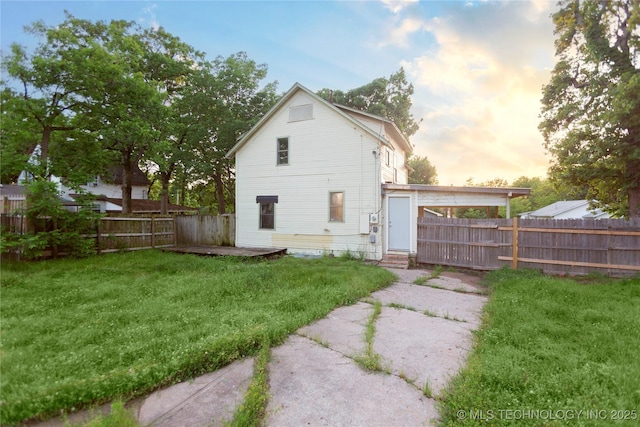 back of property at dusk featuring a yard, a fenced backyard, and entry steps