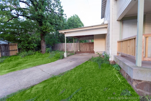 view of yard with fence, an attached carport, and driveway
