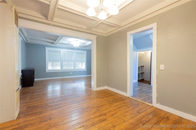 spare room featuring baseboards, wood-type flooring, coffered ceiling, and a notable chandelier