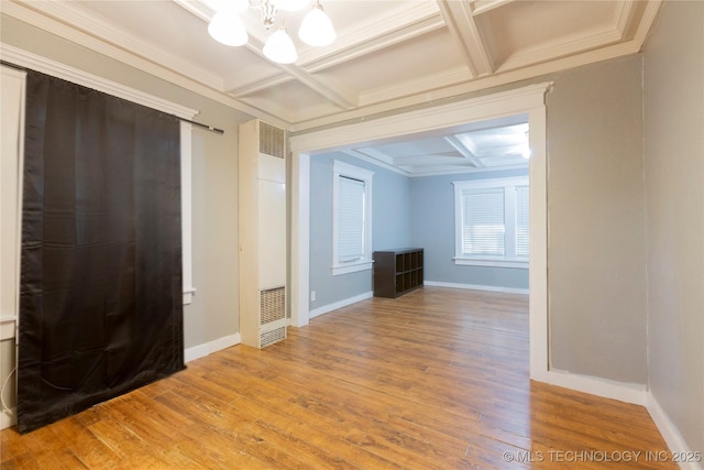 interior space with an inviting chandelier, coffered ceiling, wood finished floors, and a heating unit