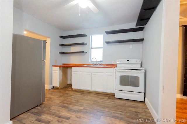 kitchen with a ceiling fan, electric range, open shelves, a sink, and freestanding refrigerator