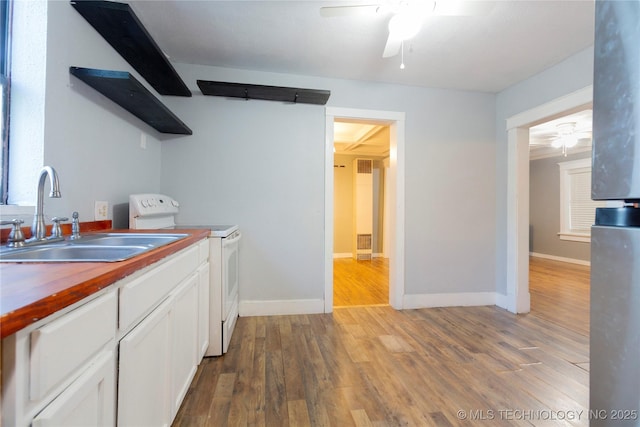 kitchen featuring a sink, a ceiling fan, white electric stove, and white cabinetry