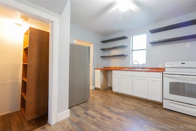 kitchen featuring wooden counters, electric range, open shelves, a sink, and freestanding refrigerator