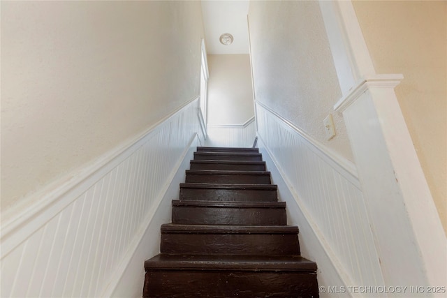 stairway with a decorative wall and a wainscoted wall