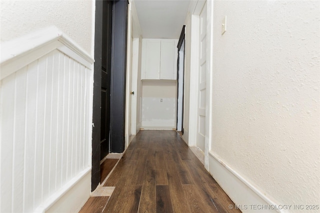 hall featuring dark wood-type flooring and a textured wall