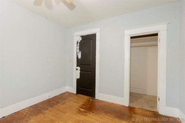 unfurnished bedroom featuring a ceiling fan, baseboards, wood finished floors, and a closet