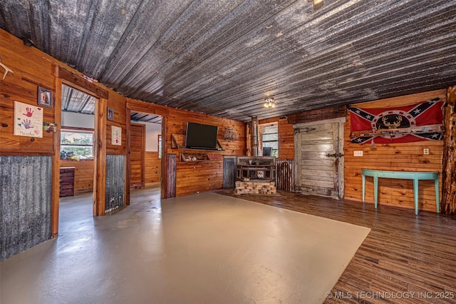 unfurnished living room with wood walls and a wood stove