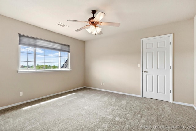 carpeted empty room featuring visible vents, a ceiling fan, and baseboards