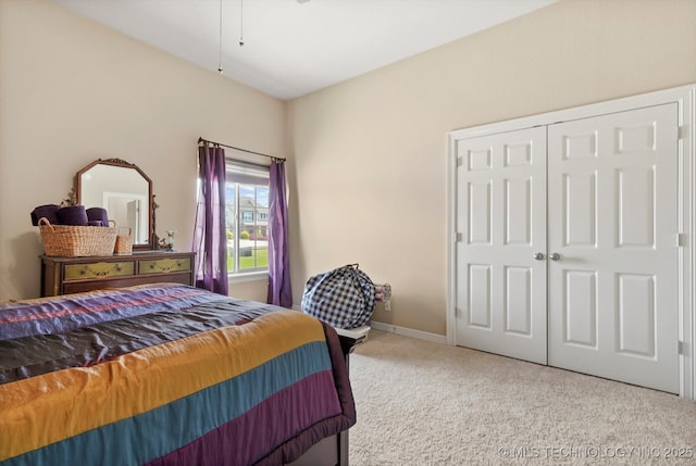 carpeted bedroom featuring baseboards and a closet
