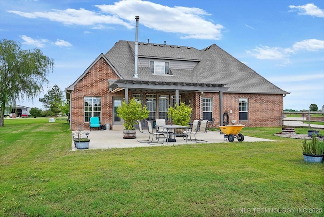 back of property with a patio, roof with shingles, a lawn, and brick siding