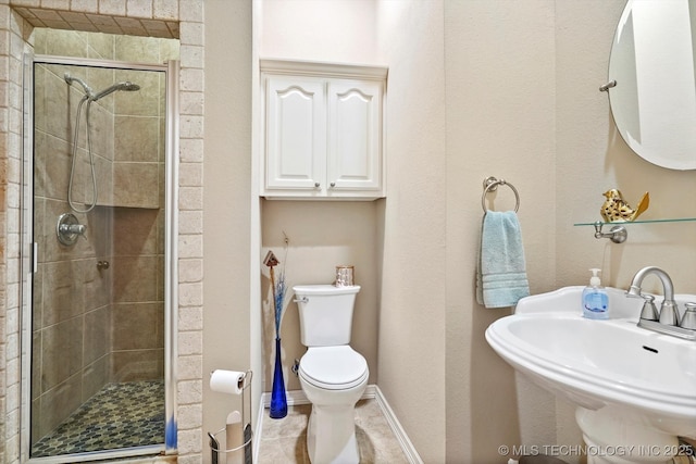 full bath with a sink, toilet, tile patterned floors, baseboards, and a stall shower