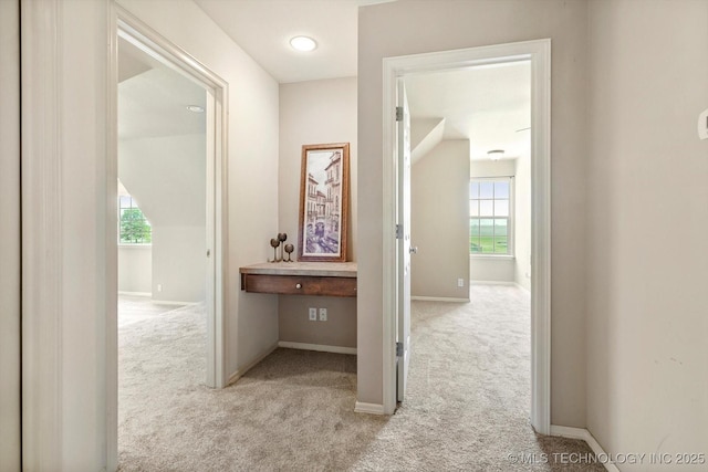 hallway featuring plenty of natural light, carpet, and baseboards
