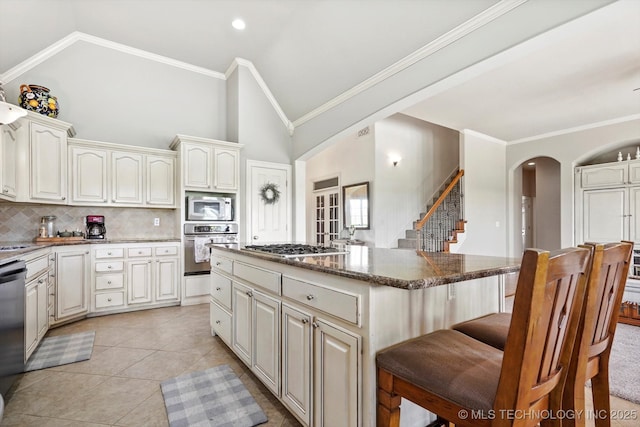 kitchen featuring a kitchen breakfast bar, decorative backsplash, a kitchen island, appliances with stainless steel finishes, and arched walkways