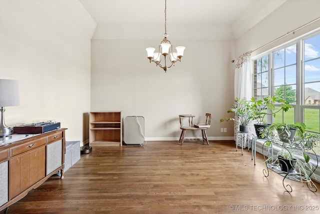 living area featuring baseboards, a towering ceiling, wood finished floors, and a notable chandelier