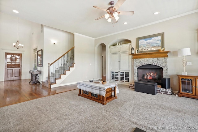 living room with arched walkways, a stone fireplace, ceiling fan with notable chandelier, recessed lighting, and wood finished floors